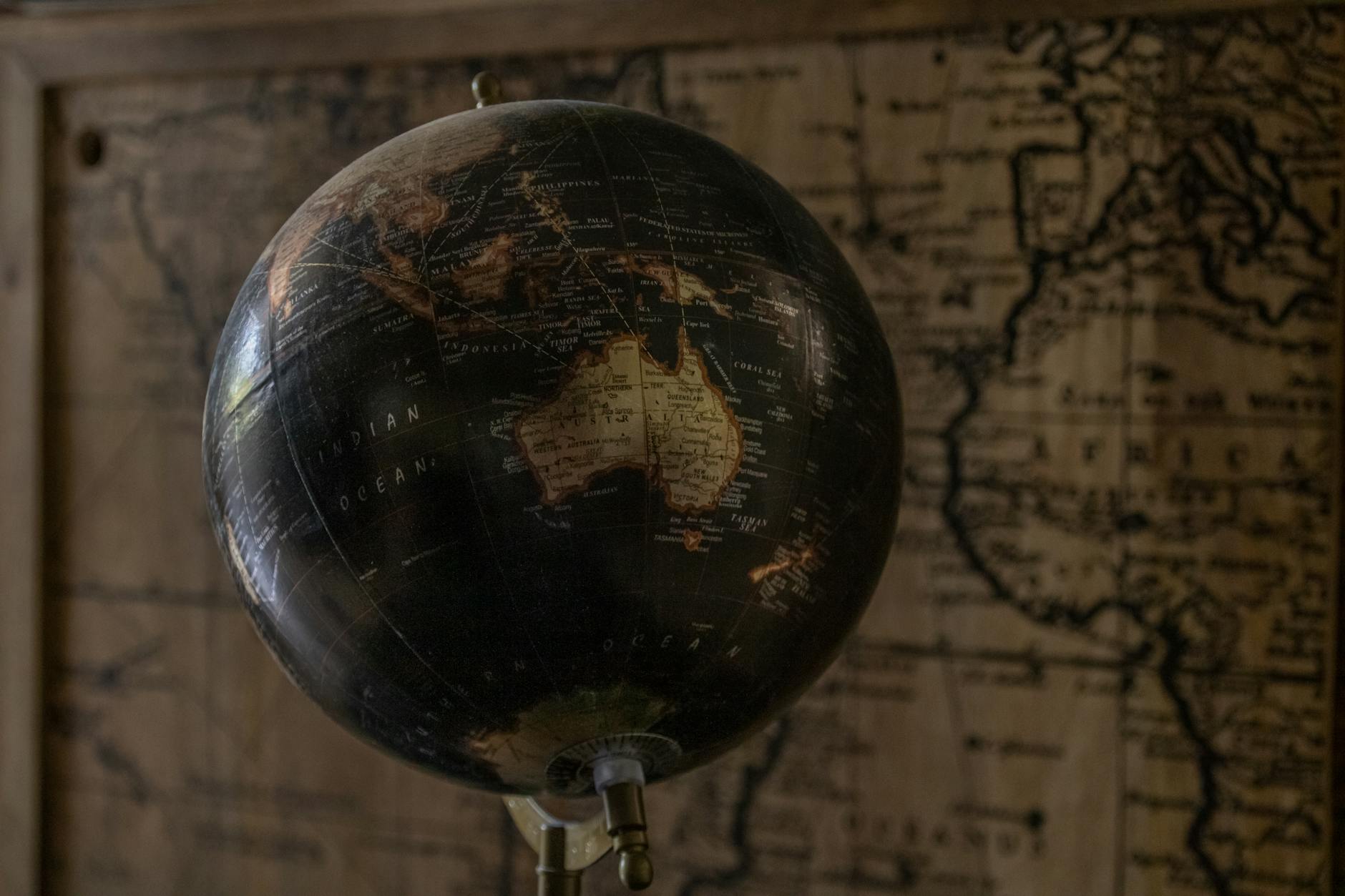 A vintage globe showcases Australia with a sepia world map in the background, offering a classic exploration theme.