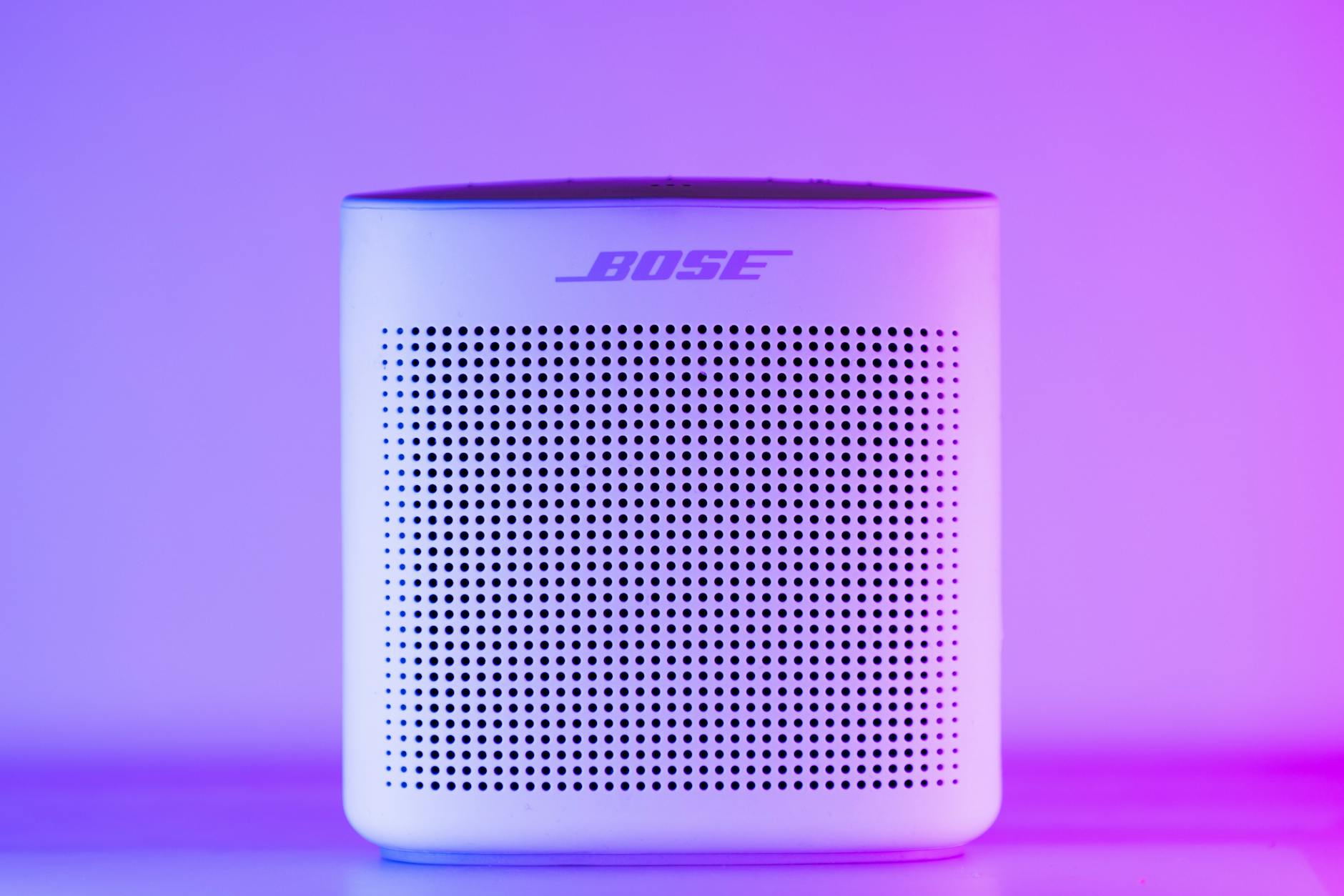 A sleek, modern Bluetooth speaker with a purple and blue light gradient, perfect for home audio setups.