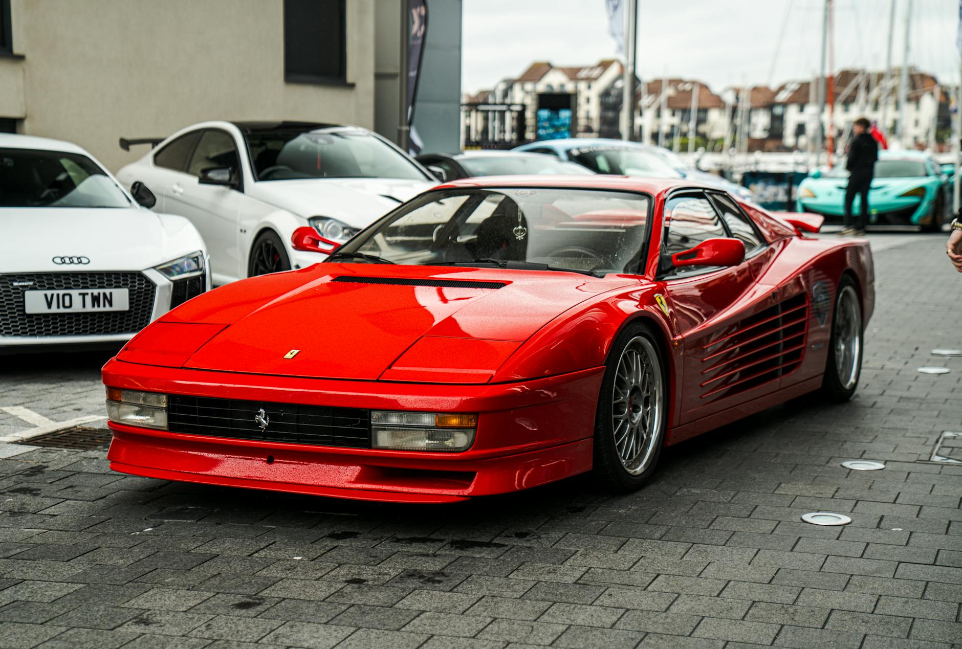 A striking red Ferrari on display at a car show in Southampton, UK, with other luxury cars around.