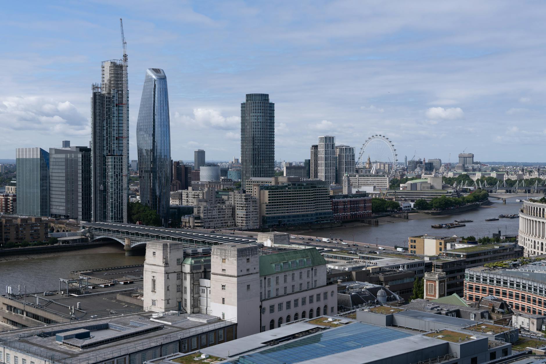 A stunning view of London's skyline with the Thames River and London Eye on a bright day.
