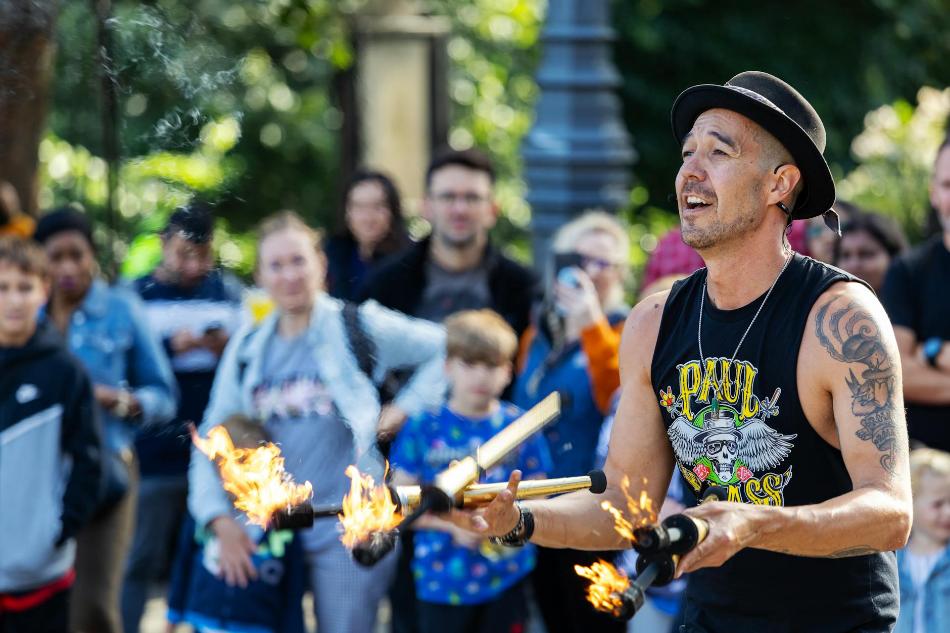 Man juggling fire in a lively street performance with a captivated audience.