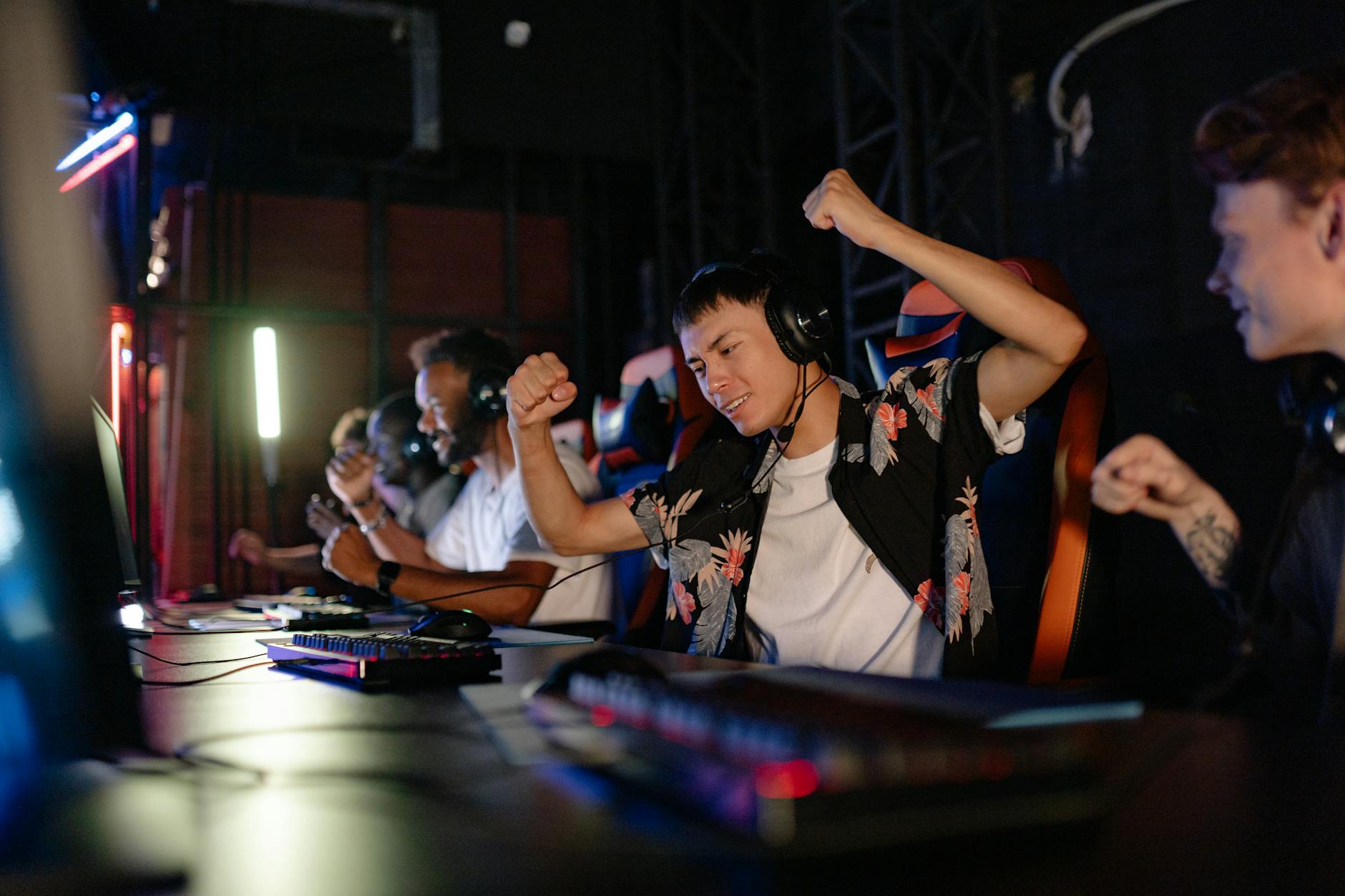 Excited gamers celebrating a win in a competitive gaming tournament with headphones.