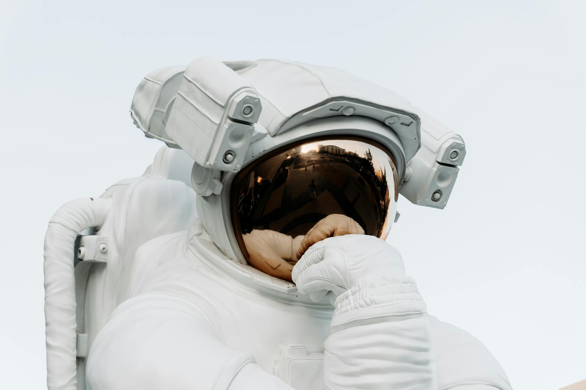 Close-up of an astronaut pondering with reflective helmet against a clear sky, embodying exploration.