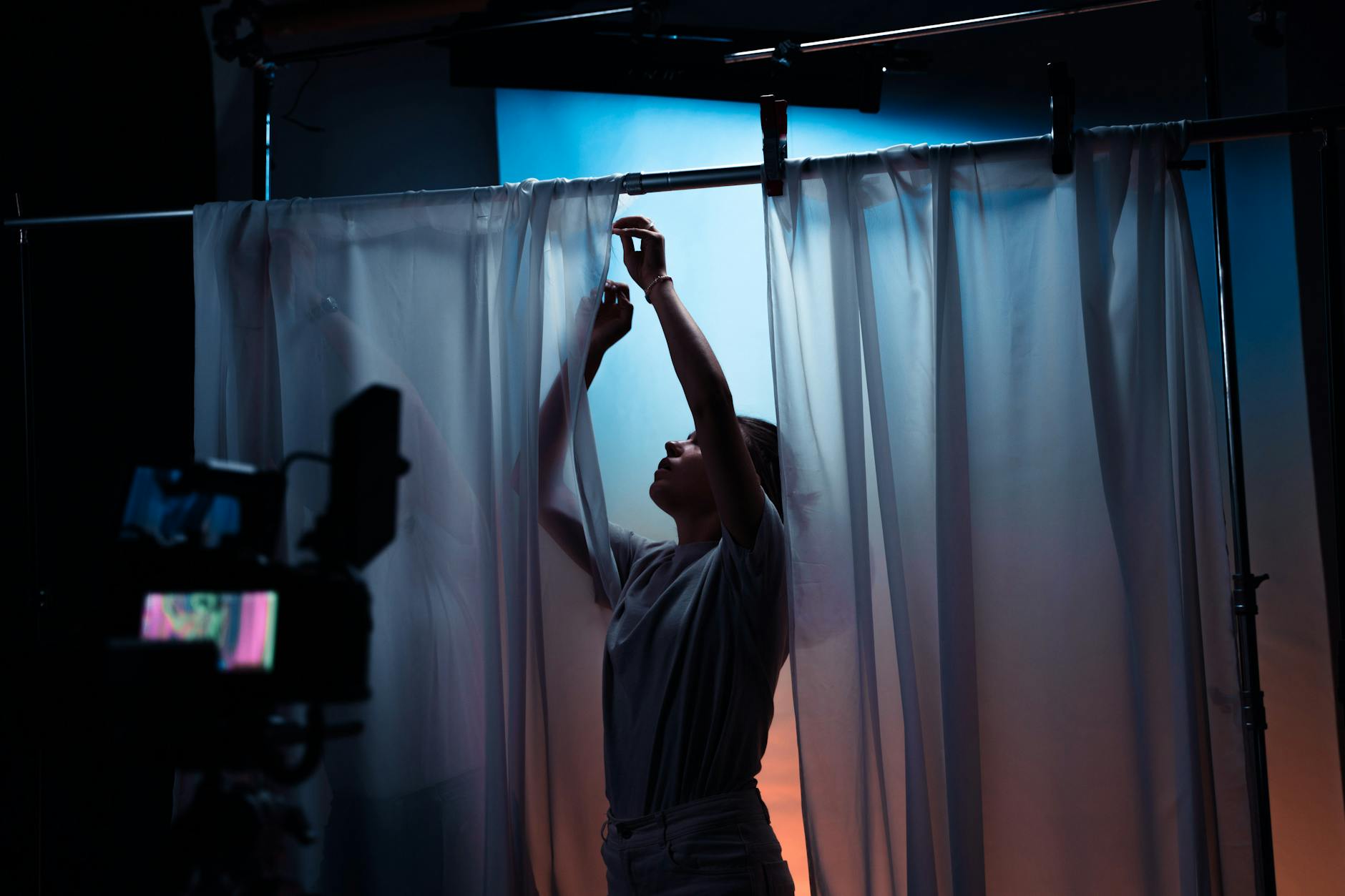 A woman adjusting curtains on a film set, highlighting cinematic setup and production.