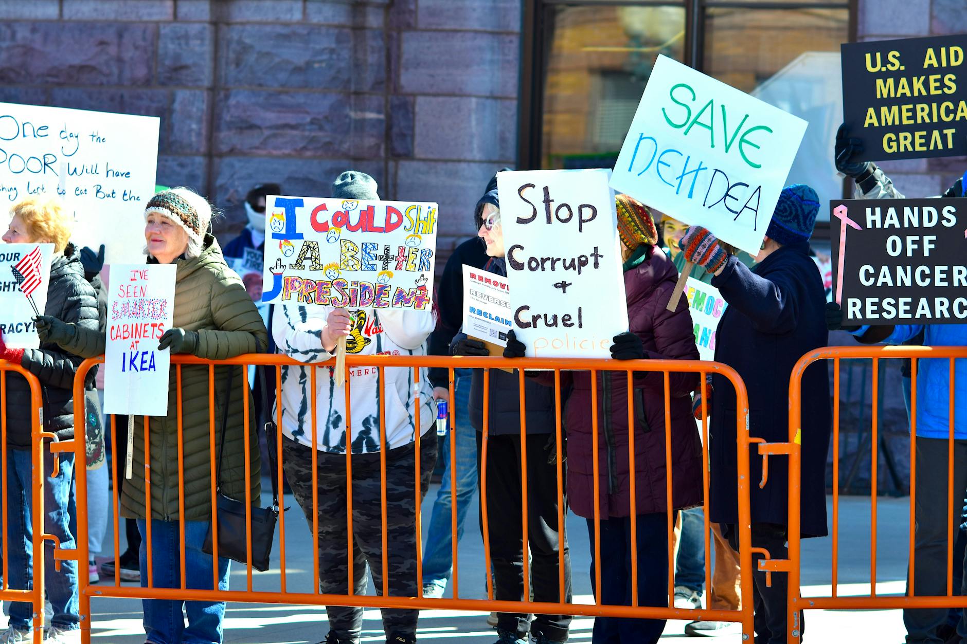 A group of people holding signs in a street protest, expressing dissent against political policies.