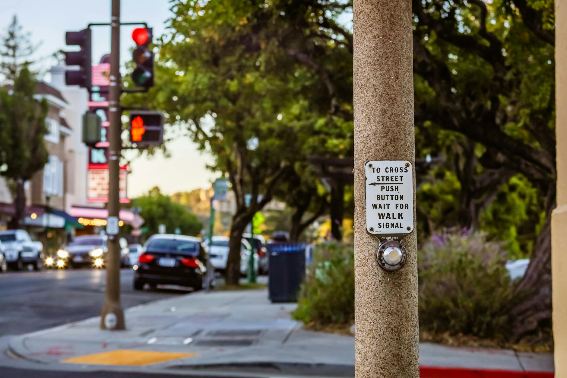 City street featuring a pedestrian crossing signal button and urban surroundings.